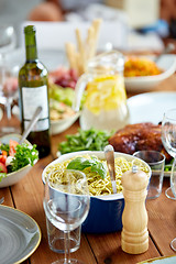 Image showing pasta with basil in bowl and other food on table