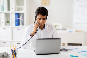 Image showing businessman calling on desk phone at office