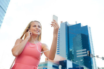 Image showing happy young woman with smartphone and earphones