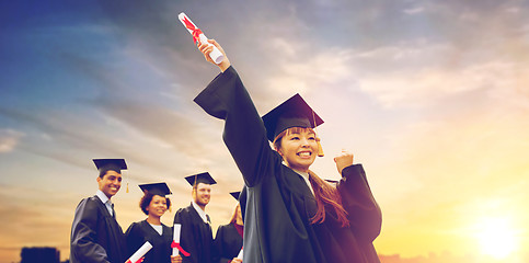 Image showing happy students in mortar boards with diplomas