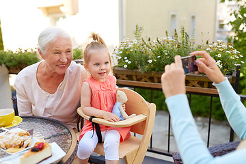 Image showing woman photographing her family at cafe