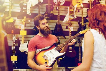 Image showing assistant showing customer guitar at music store