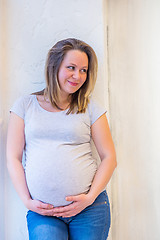 Image showing Beautiful pregnant woman standing near wall