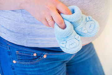 Image showing Pregnant woman holding blue baby booties