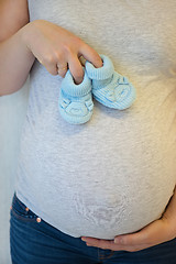 Image showing Pregnant woman holding blue baby booties