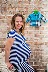 Image showing Beautiful pregnant woman sitting near wall