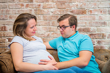 Image showing Beautiful pregnant woman and man sitting near wall