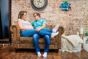 Image showing Beautiful pregnant woman and man sitting near wall