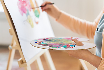 Image showing artist with palette and brush painting at studio