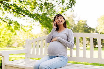 Image showing pregnant asian woman calling on smartphone at park