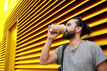 Image showing man drinking coffee from paper cup over wall