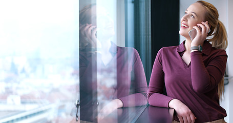 Image showing Elegant Woman Using Mobile Phone by window in office building