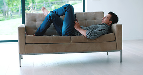 Image showing Man is Laying on Couch at Home and Using Tablet