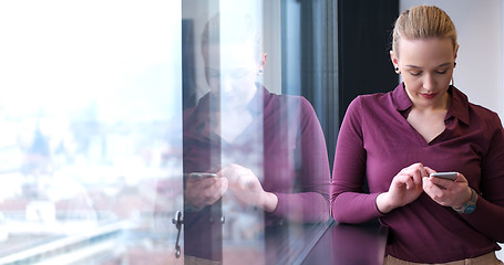 Image showing Elegant Woman Using Mobile Phone by window in office building