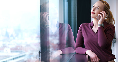 Image showing Elegant Woman Using Mobile Phone by window in office building