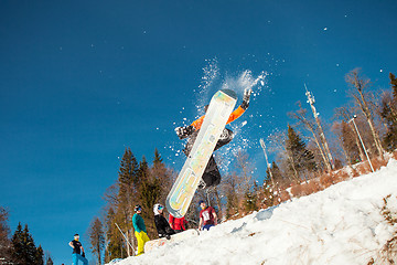 Image showing Bukovel, Ukraine - December 22, 2016: Man boarder jumping on his snowboard against the backdrop of mountains, hills and forests in the distance. Bukovel, Carpathian mountains