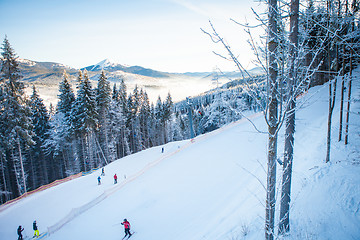 Image showing Skiers on the ski lift riding up at ski resort with beautiful background of snow-covered slopes, forests, hills in Bukovel, Ukraine