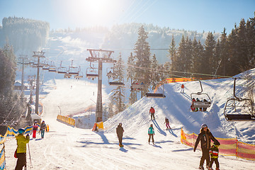 Image showing Bukovel, Ukraine - December 22, 2016: Skiers on the ski lift riding up at ski resort with beautiful background of snow-covered slopes, forests, hills in Bukovel, Ukraine