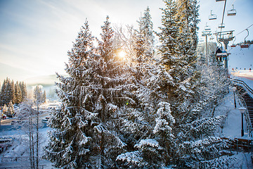 Image showing Skiers on the ski lift riding up at ski resort with beautiful background of snow-covered slopes, forests, hills in Bukovel, Ukraine