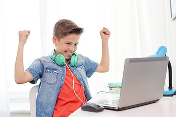 Image showing boy with headphones playing video game on laptop