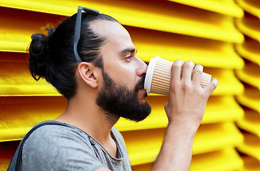 Image showing man drinking coffee from paper cup over wall