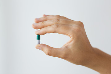 Image showing close up of hand holding capsule of medicine