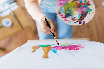 Image showing artist with palette and brush painting at studio