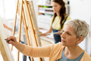 Image showing senior woman drawing on easel at art school studio