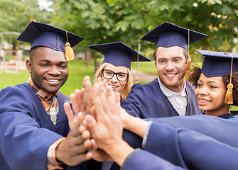 Image showing happy students in mortar boards making high five