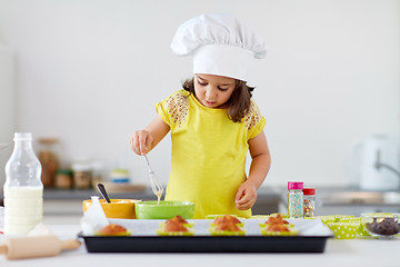 Image showing little girl in chefs toque baking muffins at home