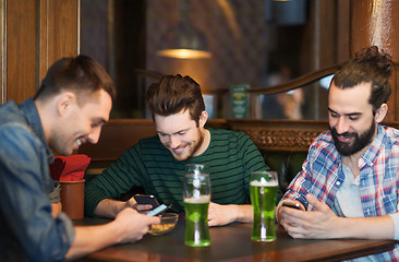 Image showing friends with smartphones and green beer at pub