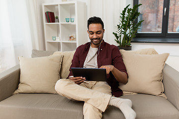 Image showing man in earphones with tablet pc listening to music