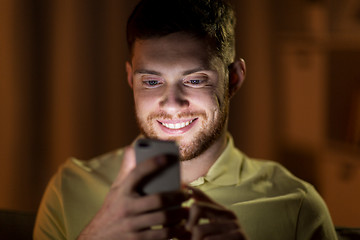 Image showing happy young man with smartphone at night