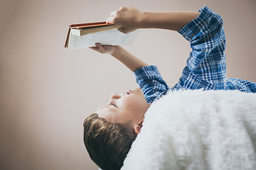 Image showing little boy is lying on the bed and reading a book