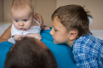 Image showing father and sons lie on the bed.