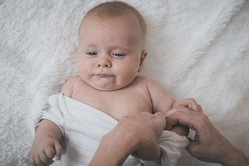 Image showing mom dresses the baby on the bed