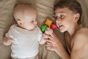 Image showing little boy playing with newborn on the bed 