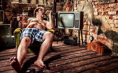 Image showing Fat man eating a hamburger sitting on a chair in the slums