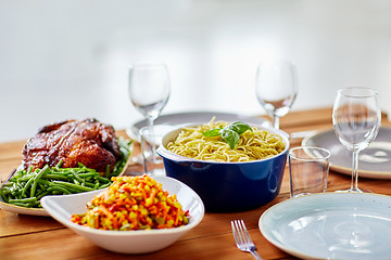 Image showing pasta with basil in bowl and other food on table