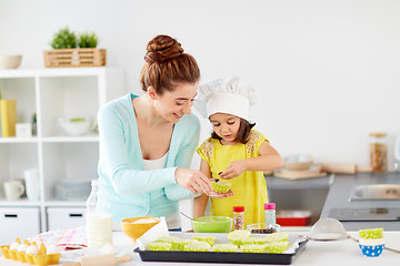 Image showing happy mother and daughter baking cupcakes at home