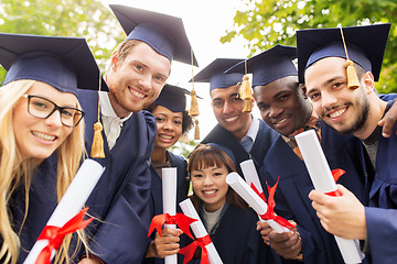 Image showing happy students in mortar boards with diplomas