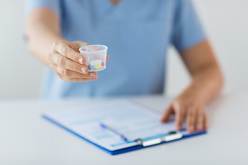 Image showing close up of doctor with pills in medical cup