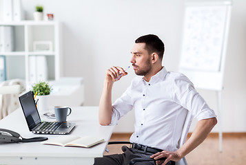 Image showing businessman with laptop and notebook at office