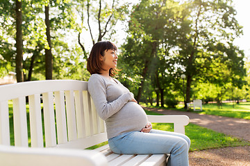 Image showing happy pregnant asian woman sitting on park bench