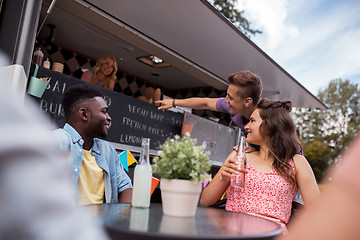 Image showing friends with drinks sitting at table at food truck