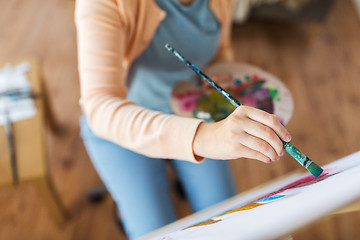 Image showing artist with palette and brush painting at studio