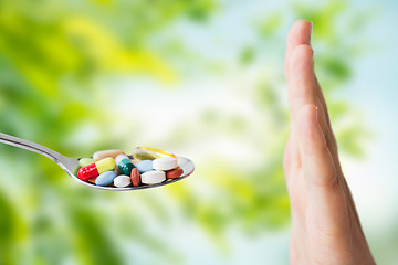 Image showing hand of woman refusing from pills on spoon