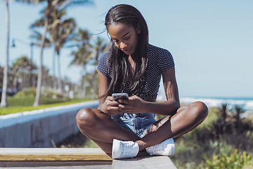 Image showing Beautiful woman using phone on fence