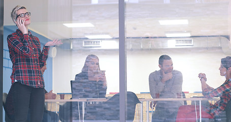 Image showing Business Woman Looking Through A Window And using On A Cell Phon