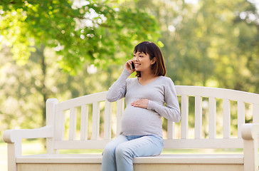 Image showing pregnant asian woman calling on smartphone at park